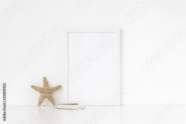 Fototapeta Minimal white frame mockup A4 in interior with sea elements . Frame mock up background for bloggers, social media, lettering, art and design. Indoor, frame on table. Summer sea mood