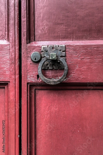 Fototapeta An old weathered and worn red door on a building