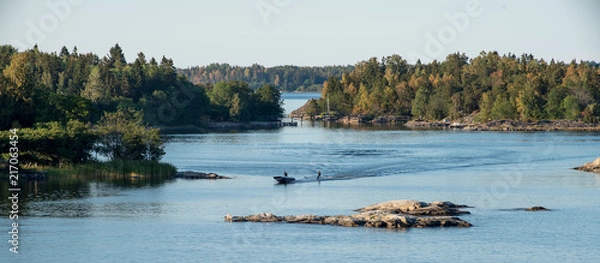 Obraz Summer vacation idyll in Sweden - A panorama view of Stockhol archipellago showing the sea, small islands and a motor boat towing a person on water skis.