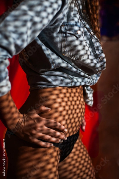 Fototapeta Shadows in the form of small squares fall on the body of a undressing girl
