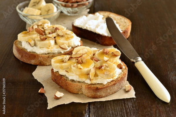 Fototapeta Toast with cream cheese, topped with banana, almonds and honey