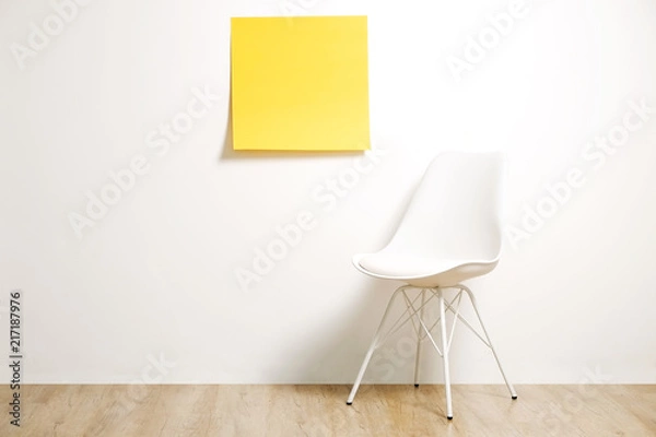 Fototapeta Single empty loft style chair on wooden floor with blank ad poster and white wall background, yellow sticker with copy space for your text. Interview invitation for vacant position concept. Close up.