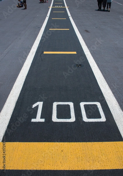 Obraz One hundred meters, runway on an aircraft carrier(abstract meaning apply for one hundred).Number" 100 "on white and yellow runway.Takeoff runway and runway aircraft carrier on battleship. Public area.