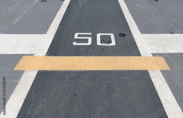Obraz Number " 50 " on white and yellow runway. Takeoff runway and runway aircraft carrier on battleship. Public area.