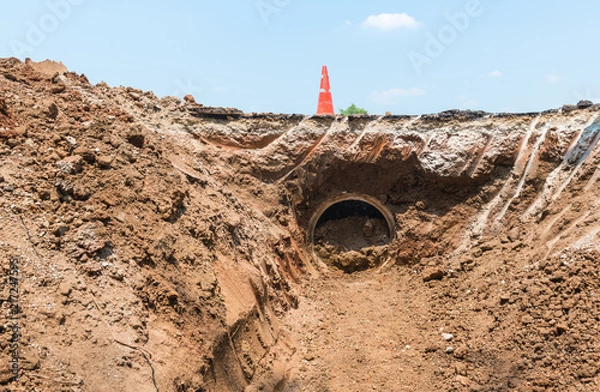 Fototapeta Concrete Drainage Pipe on a Construction Site near traffic cone .Concrete pipe stacked sewage water system aligned on site.