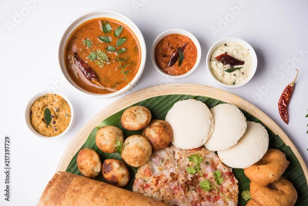 Fototapeta Group of South Indian food like Masala Dosa, Uttapam, Idli/idly, Wada/vada, sambar, appam, semolina halwa, upma served over banana leaf with colourful chutneys, selective focus