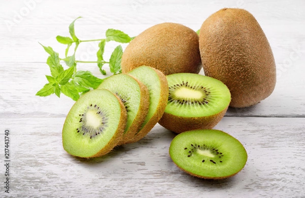 Obraz Zielone kiwi i liście mięty na białym tle drewna