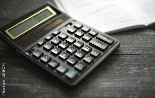 Obraz horizontal background with a calculator on a dark wooden surface of the table