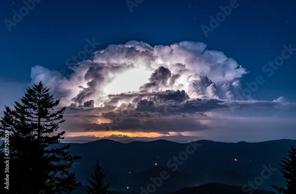 Fototapeta A huge thunderstorm with active lightning lighting up the clouds is seen from the high peak of Spruce Knob in the Appalachian Mountains of West Virginia