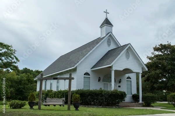 Fototapeta White country church with wooden siding and cross on the cupola
