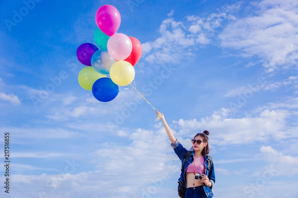 Obraz girl's travel and holds a ball of light color on a bright day sky background