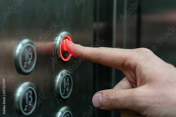 Obraz the man presses the elevator button with the red light.