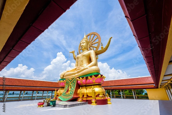 Fototapeta Large gold buddha statue in a sitting position under the blue sky at Big Buddha Temple is a famous tourist destination of Koh Samui island, Surat Thani province, Thailand