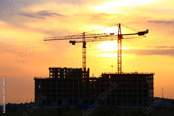 Fototapeta construction with tower cranes on a bright sunset background