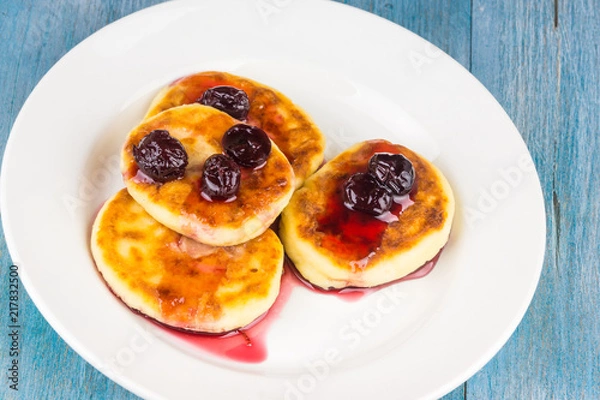 Fototapeta Russian cheesecakes with cherry jam on a white plate