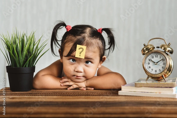 Fototapeta cute and confused lookian asian toddler with question mark on her forehead. concept of child learning education, growth and development.