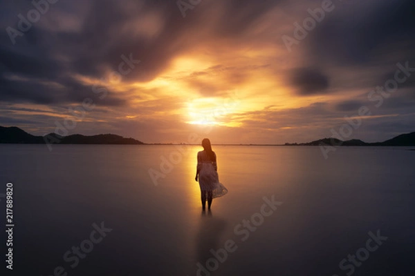 Fototapeta A lonely girl is walking along island coastline and has reflection on wet sand.