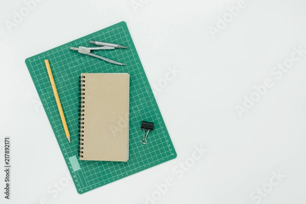 Fototapeta Table top view aerial image of back to school of education season background concept.Flat lay paper green rubber cut board with note nook and pencil on modern rustic white wooden.Free space for text.