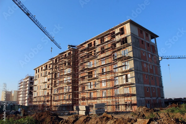 Fototapeta Large construction site including several cranes working on a building complex