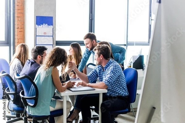 Fototapeta Business colleagues sitting at the table compete with each other arm wrestling