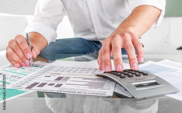 Fototapeta Close-up of a Person Analyzing Business Graphs with Calculator