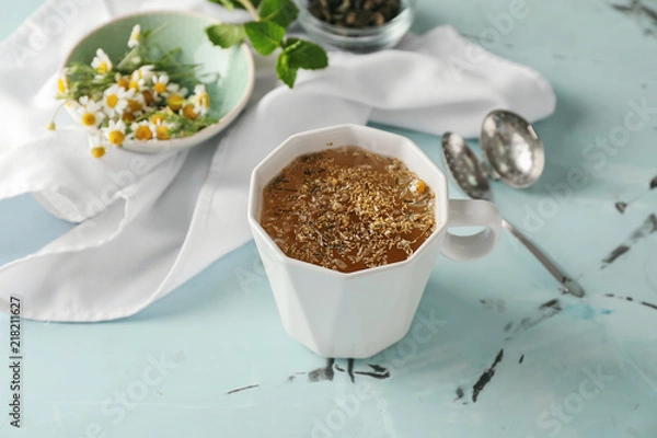 Fototapeta Cup of delicious camomile tea on light table