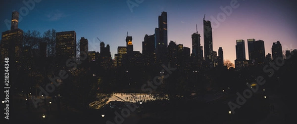 Fototapeta ice rink dawn panorama view from central park to the skyscrapper of new york city with ice skating