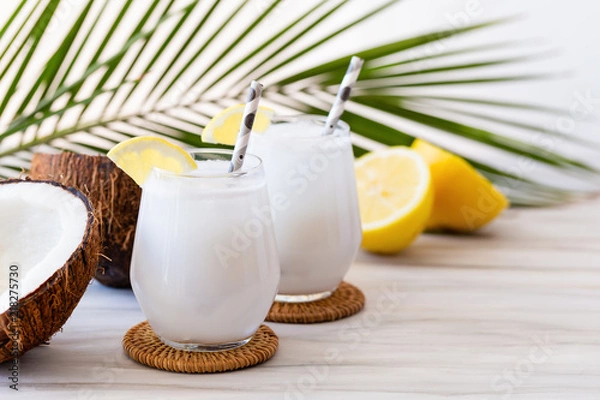 Fototapeta Coconut cocktail in glasses with lemon and drinking straw. White background. Copy space