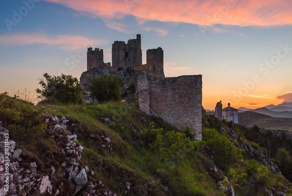 Fototapeta Rocca Calascio (Italy) - The ruins of an old medieval village with castle and church, over 1400 meters above sea level on the Apennine mountains in the heart of Abruzzo, at sunset.