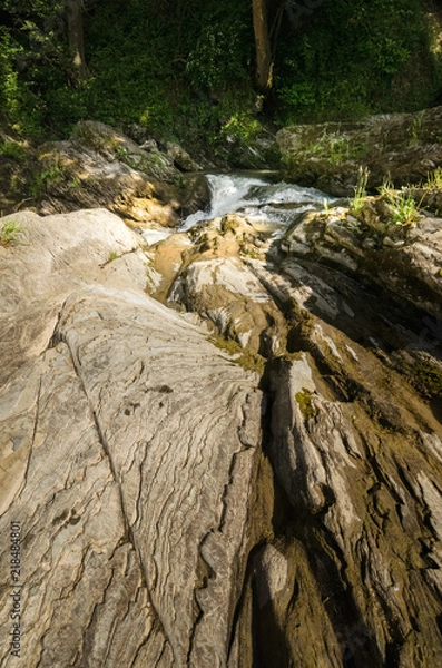 Fototapeta Wide angle shot of mountain river with a waterfall flowing between rocky coasts. Expressive foreground. Taken from low point of view at sunny spring day at Carpathian mountains. Natural background. 