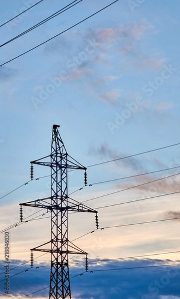 Fototapeta Tall electrical tower with a powerlines on the beautiful sunset background