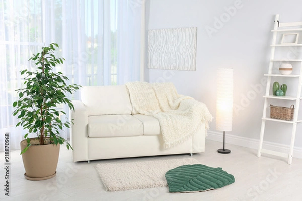 Fototapeta Stylish living room interior with sofa and houseplant near white wall