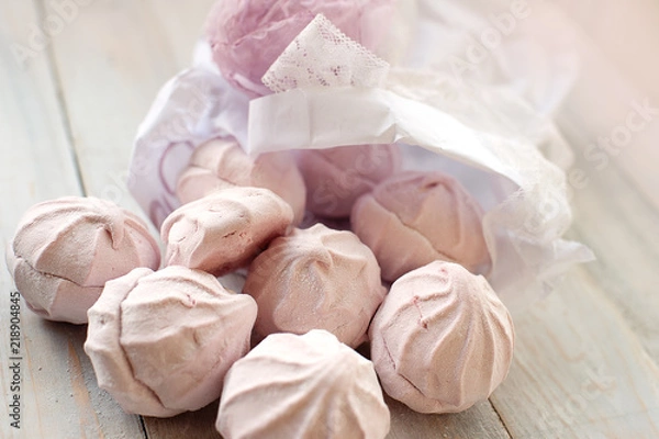 Fototapeta Tasty pink zephyr on a wooden table. It can be used as a background