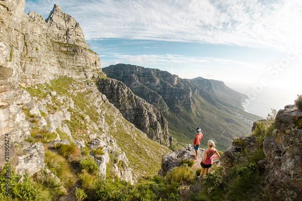 Fototapeta Two trail runners enjoying the view of Table Mountain and the ocean in Cape Town South Africa