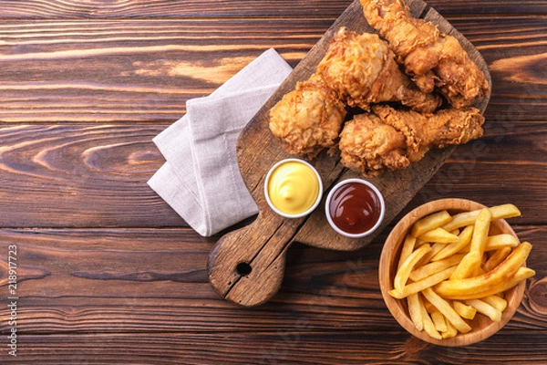Fototapeta Crispy chicken legs and french fries potatoes. Fast junk food