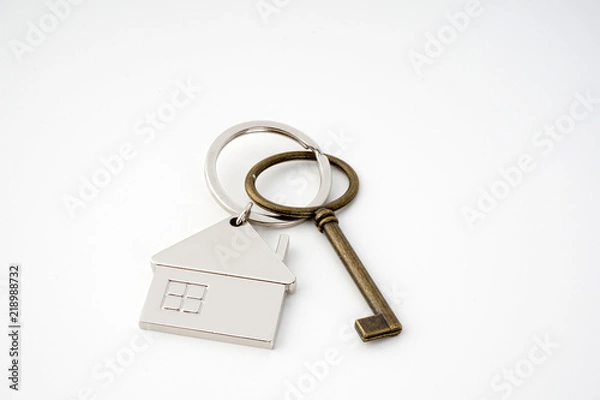 Fototapeta Key and keychain in the shape of a house isolated on white background.