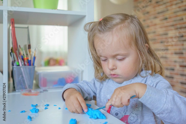Fototapeta Baby girl toddler playing and learning with plasticine, close-up shot
