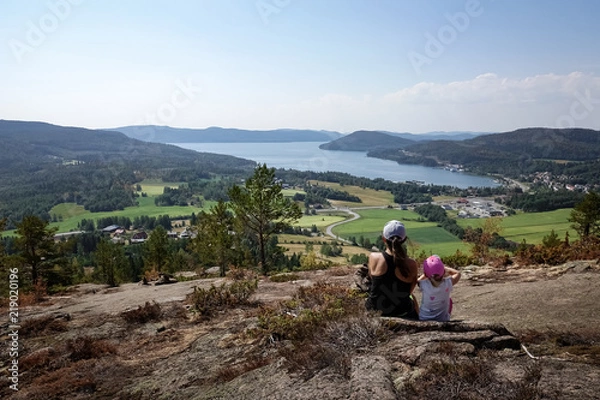 Fototapeta Family travel. Mother and daughter rest from hiking uphill a mountain. Beautiful view of archipelago, mountains, forest and sea. Skule mountain, high coast in northern Sweden.
