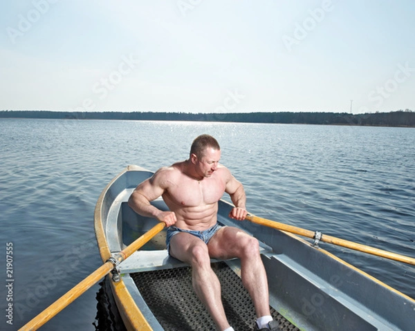 Fototapeta Muscular man with oars in boat
