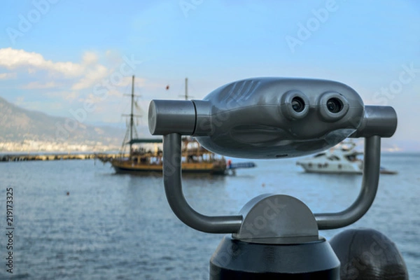 Fototapeta Panoramic binoculars standing on the shore. Ship at sea. Binocular looks at the ships at sea.