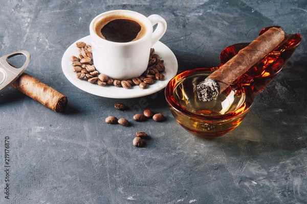 Fototapeta Cup of coffee, coffee beans, ashtray with cigar on dark background