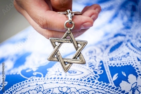 Fototapeta Young woman's hand holding a Star of David - Magen David key chain. The State of Israel, Holocaust remembrance, Judaism, Zionism concept image.