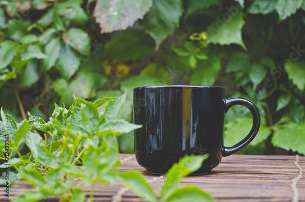 Obraz A single solo blank black coffee mug on the wooden table in the backyard. 