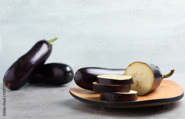 Fototapeta Wooden board with ripe eggplants on table