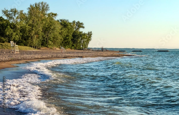 Fototapeta Deserted beach with lifeguard chairs and trees in background on Presque Isle on Lake Erie