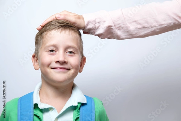 Obraz Ręka na głowie ładny uczeń z niebieskim plecakiem na białym tle. koncepcja pochwały