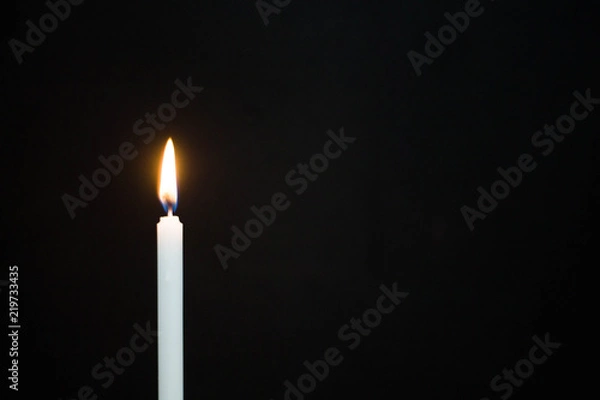 Fototapeta One light candle burning brightly on black background