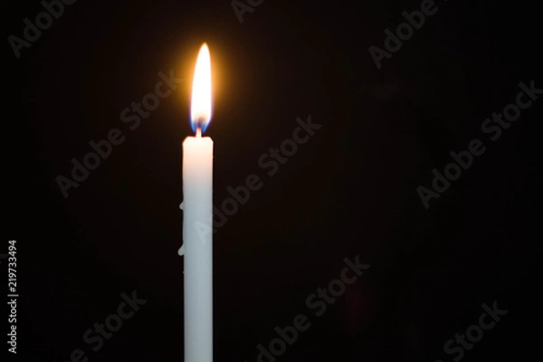 Fototapeta One light candle burning brightly on black background