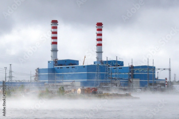 Fototapeta A modern CCGT thermal power plant in a fog on the shore of a cooling reservoir.