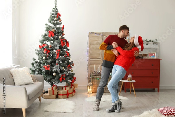 Obraz Happy young couple dancing near Christmas tree at home